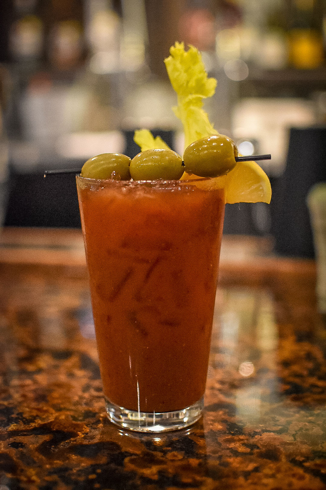 Image: A Bloody Mary with three olives sitting on a bar