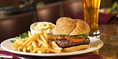 Image: Burger, fries and cole slaw on plate with beer in background